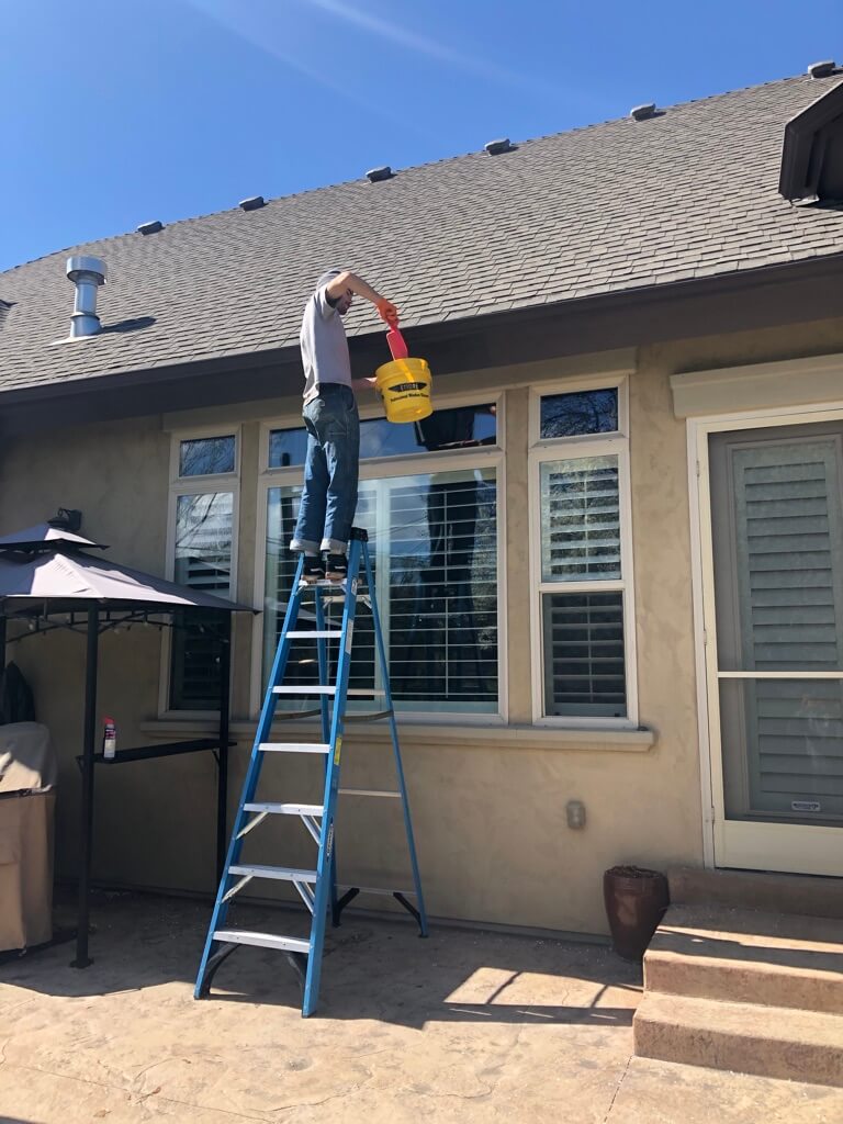 Cleaning gutters and removing debris by hand.