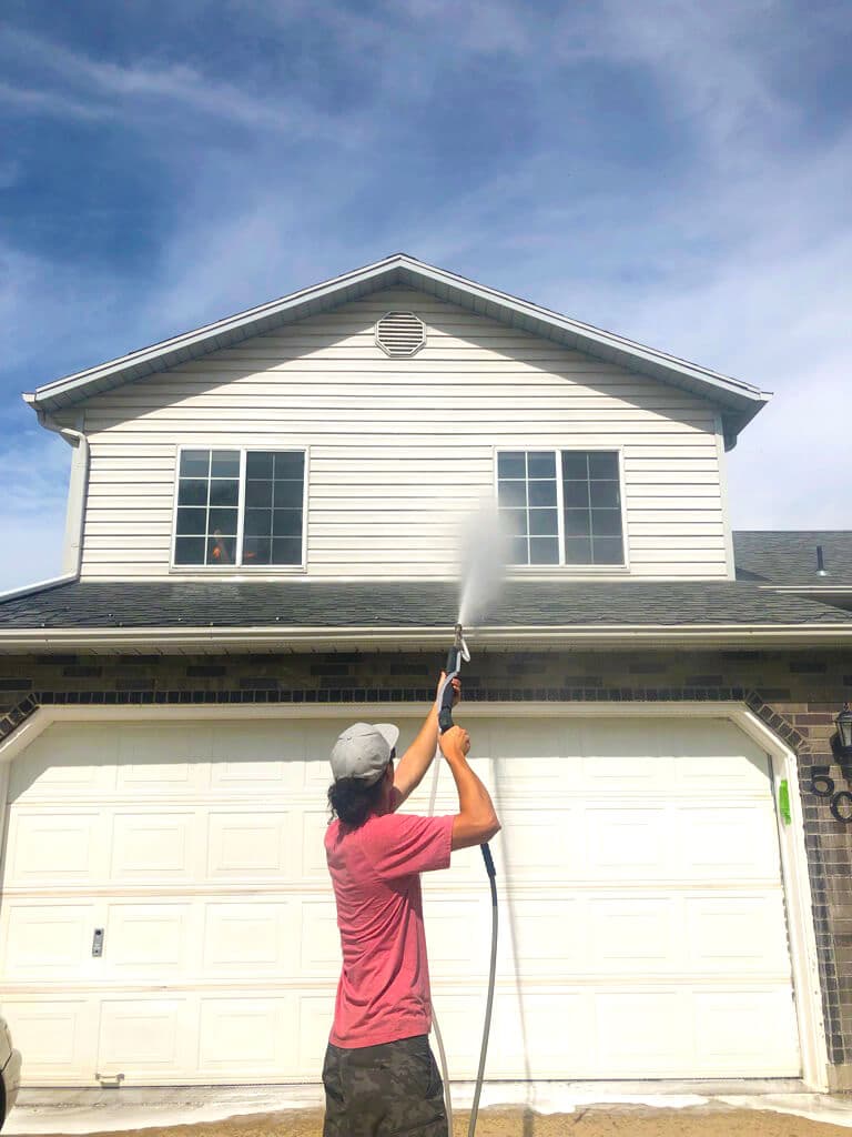 Soft house washing being performed above the garage.