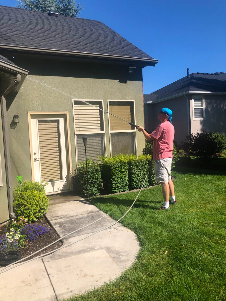 A final rinse on a house after a professional house washing.